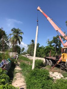 crane lifts post into hole